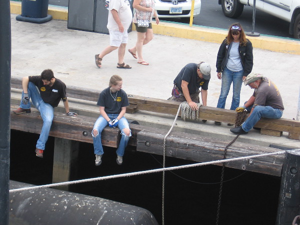 More museum volunteers handling ropes and chains by the water.