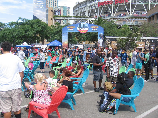 People relax and watch a demo video game up on a big screen.
