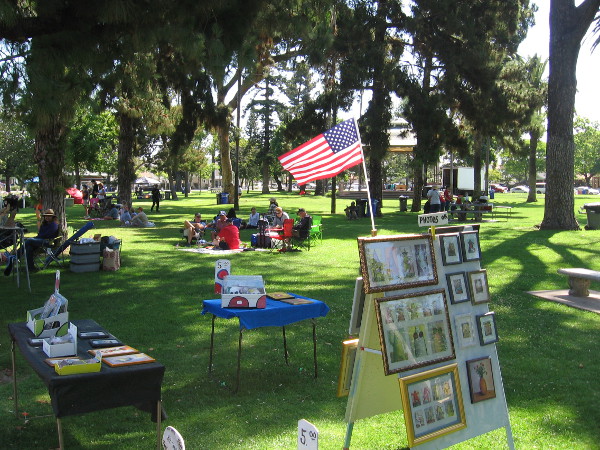 People relax and look at artwork for sale in Spreckels Park. An afternoon concert in the park features patriotic music.