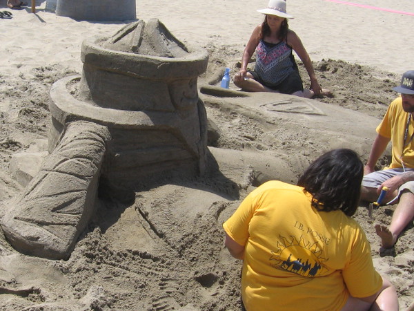 A kid is surrounded by Superman and other imaginary superheroes. He wears a fireman's helmet.