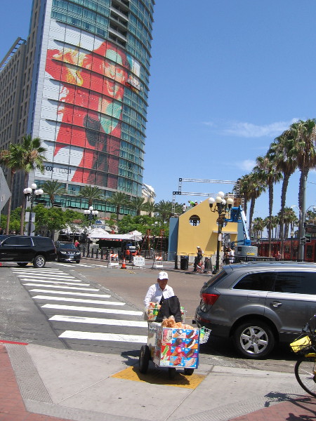 An ice cream vendor crosses Fifth Avenue. The Gifted wrap on the Omni appears above the offsite for The Good Place, now under construction.