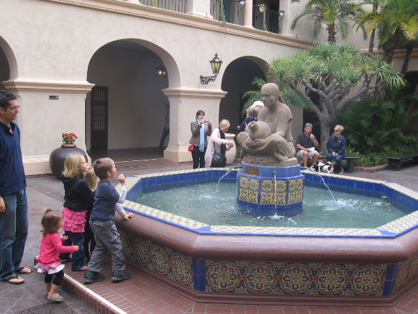 Children gaze at the beautiful fountain and sculpture Woman of Tehuantepec by Donal Hord, in the courtyard of Balboa Park's House of Hospitality.