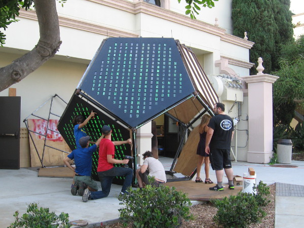 Working to complete Unfolding Humanity. Lit green lettering on the exterior of the sculpture is similar to that from the iconic movie The Matrix.