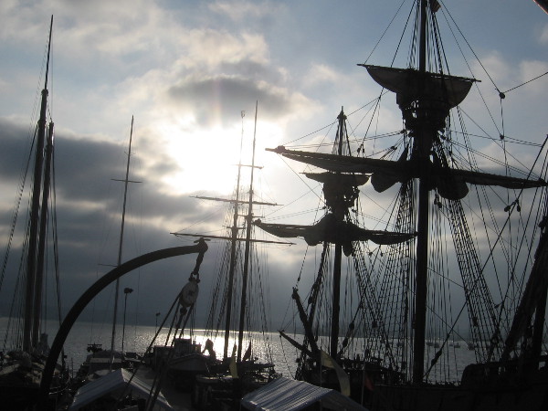 The sun shines out from behind clouds, and the masts of America, Californian and San Salvador.