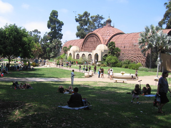 People relax and picnic on the lawn near the Botanical Building.