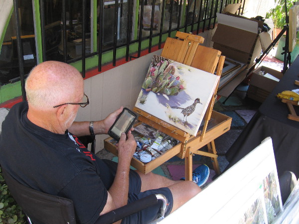 A painter creates new artwork outside the window of the Southwestern Artists' Association Gallery in Studio 23.