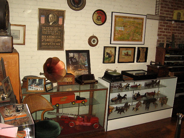 One wall and a couple of glass display cases filled with fantastic old collectibles and Americana.