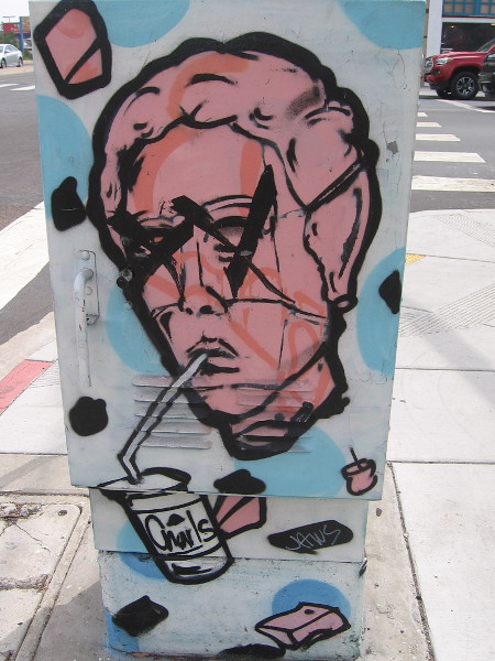 Drinking through a straw on the sidewalk.