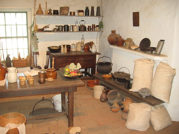Jars, pots, sacks of flour and fruit are among the many items seen in the rather primitive kitchen.