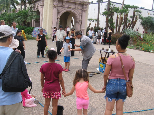 Street magician Kenny Shelton delights some young people with one of his amazing tricks.