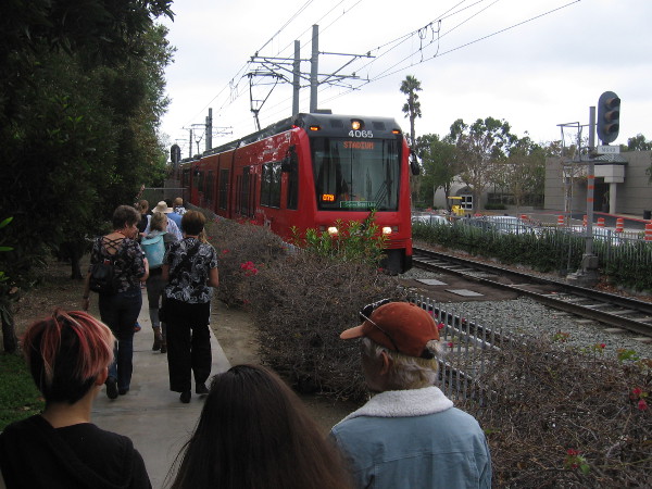 The audience heads west along the San Diego Trolley tracks.