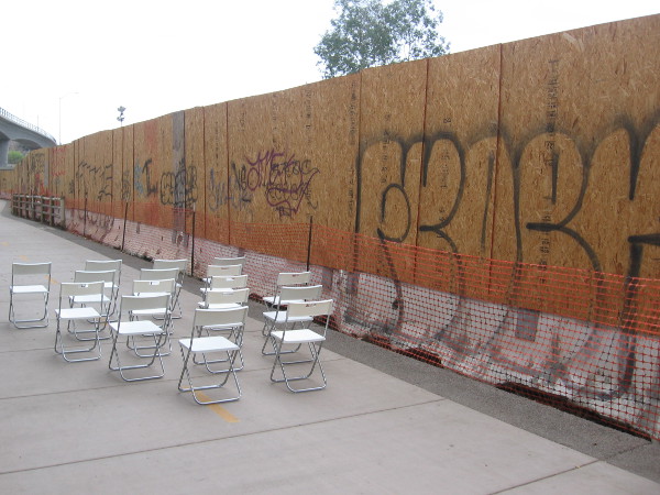 Empty chairs and graffiti on a construction wall await at the next Trolley Dance stage.