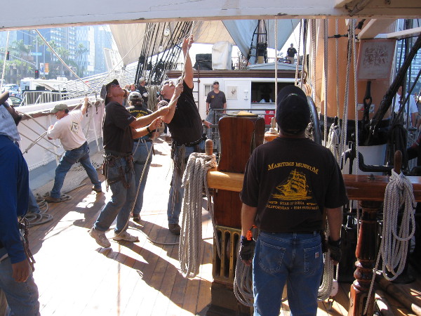 Pulling ropes to manipulate the yards and sails.