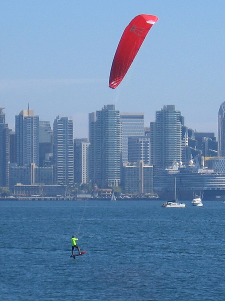 A highly skilled kite boarder flies above the blue water of San Diego Bay.