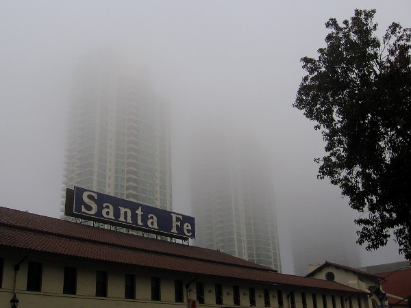 The historic train station's Santa Fe sign stands out when contrasted with nearby fog engulfed high-rises.