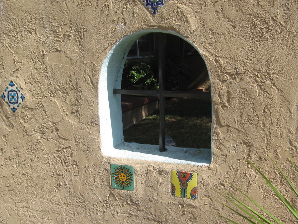 Some small colorful tiles in a stucco wall.