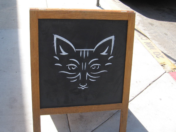 Abstract cat on a sidewalk chalkboard.