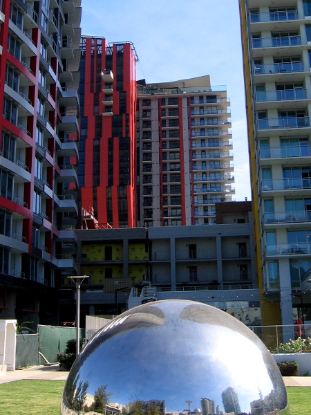 Colorful new residential high-rises beyond one of the two silvery spheres at Fault Line Park in East Village.