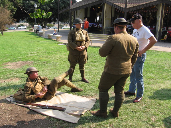 Guys dressed as soldiers hang out on the grass by the Balboa Park Carousel, which itself is over a hundred years old.