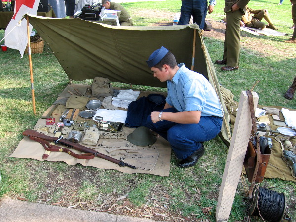 A rifle, canteen, helmet, and other equipment from the battlefield displayed on a blanket.