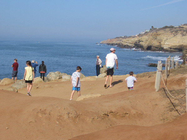 Families enjoy the warm sunshine and smell of the ocean. This photo looks north along the sandstone cliffs of Point Loma.