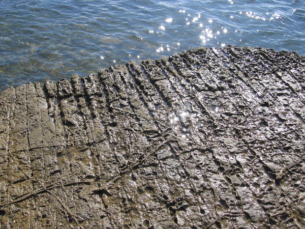 The rock shelf contains parallel fissures and oddly eroded patterns. Over many years the rock is weathered, strangely changes.