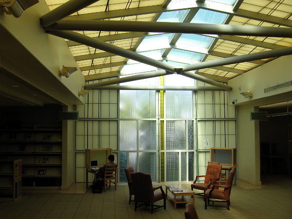 Someone reads near the sail-like cast glass panels of the north window inside the La Jolla Library.