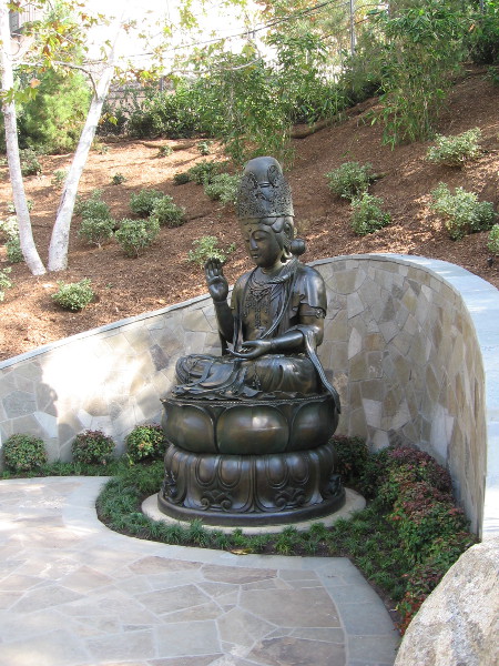Kannon Bosatsu sits tranquilly in a beautiful corner of the Japanese Friendship Garden near the source of a new stream.