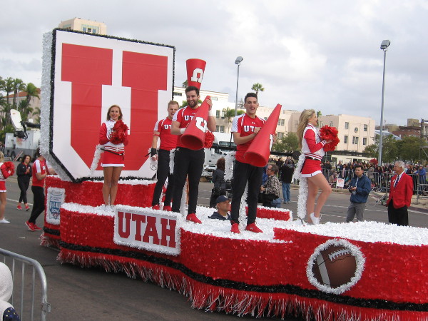 The red and white Utah Utes float with smiling cheer squad passes by.