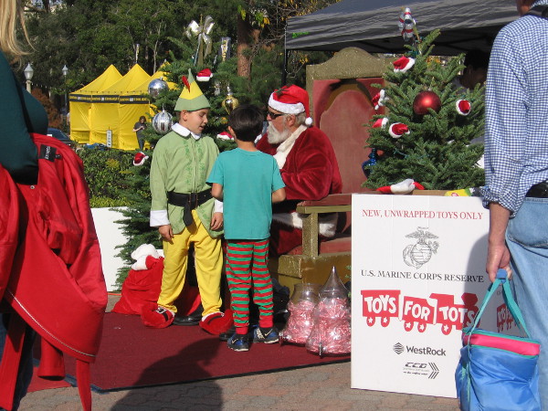 Elsewhere in the rear of the Spreckels Organ Pavilion, Santa confers with an elf before a photo is taken.