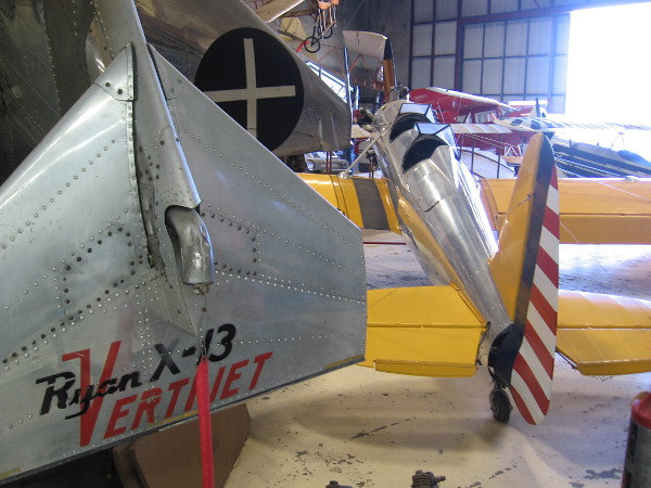 Looking past the Ryan X-13 Vertijet at other exhibits in the annex hangar, including a yellow Ryan Recruit military trainer.