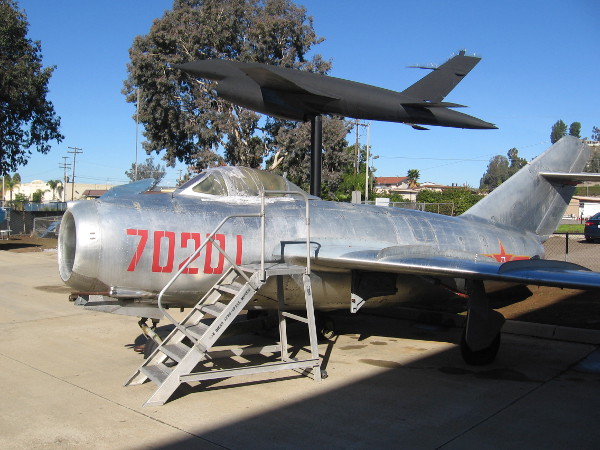 The aircraft in the foreground is a Mikoyan-Gurevich MiG-15. Mounted beyond it is a Ryan Model 147 Lightning Bug jet-powered reconnaissance drone.