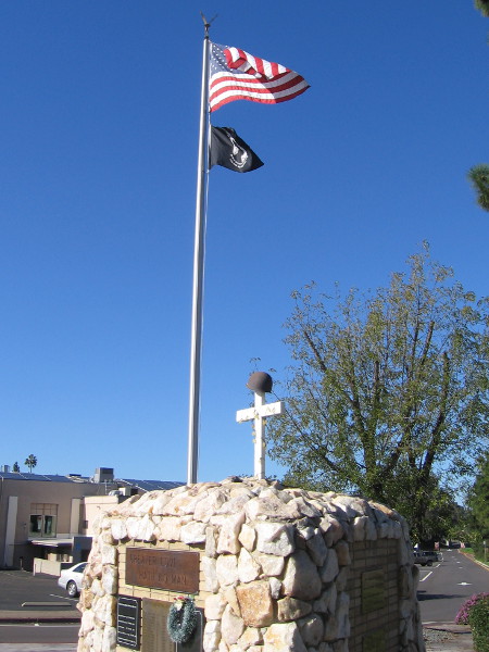 Flags fly in the January breeze. A helmet atop a cross, signifying those killed during the Vietnam War.