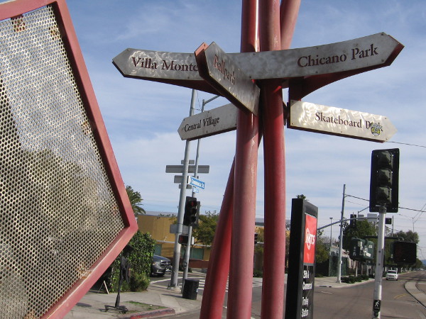A sign at the trolley station points to various locations of interest, including Villa Montezuma and Chicano Park.