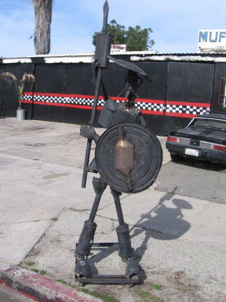 A metal Don Quixote stands guard by a muffler shop.