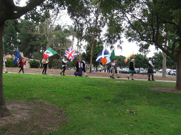 Flags of many nations follow a bagpiper through Balbo Park as the annual International Dance Festival is about to begin.