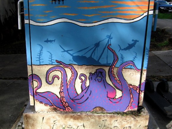 An octopus at the bottom of the sea near a wrecked tall ship.