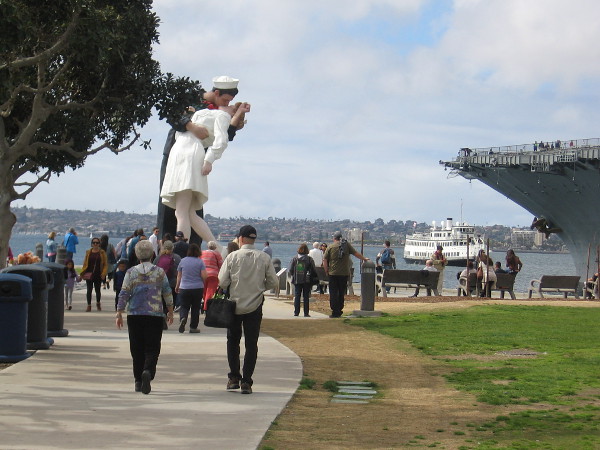 Visitors to San Diego move through the Greatest Generation Walk toward the Embracing Peace statue.