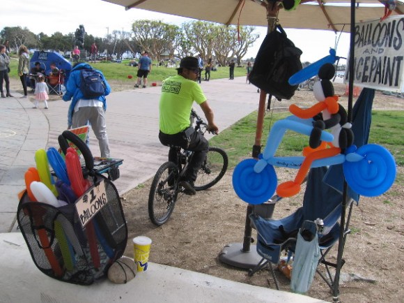 A balloon twister guy heads off on his bike.