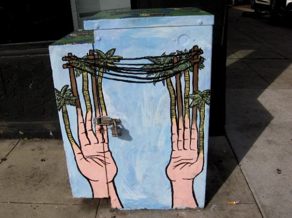 The fingers painted on this electrical box transform into palm trees and telephone poles!