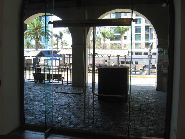 Looking west out glass doors at the Figi Family Concourse and trolley and train platforms at Santa Fe Depot.