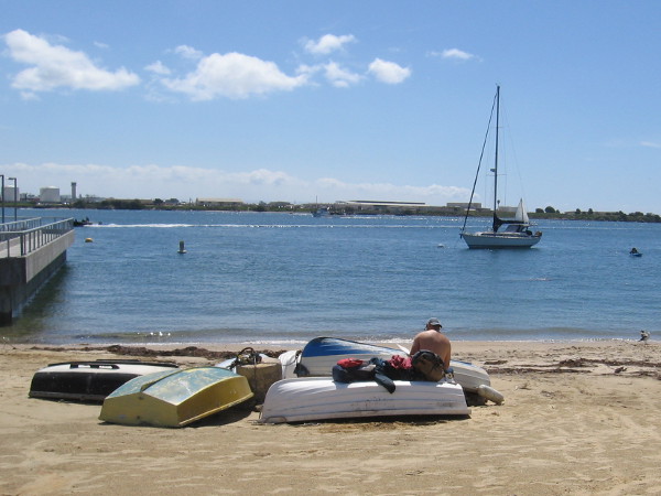 Someone hangs out nearby, sitting among beached dinghies.