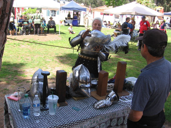 A member of the group Swords of Chivalry removes her steel helmet after some mock medieval combat.