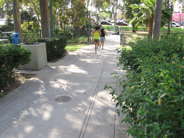 People jog along a walkway which features tracks that wind through the park like the old trolley line.