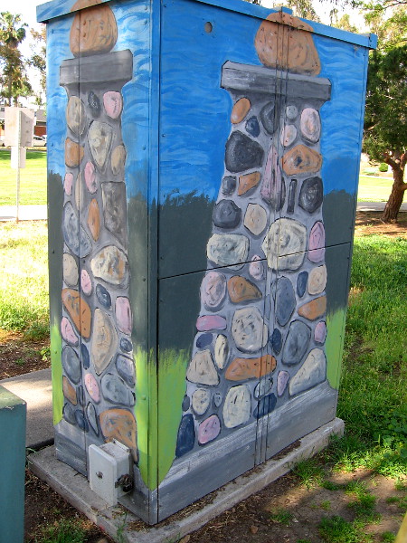 An electrical box at the edge of the park is painted like a cobblestone post, one of the symbols of University Heights.