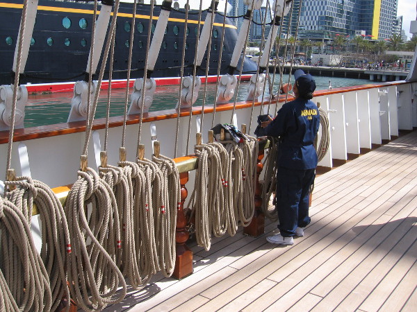 A crew member on deck tends to some ropes.