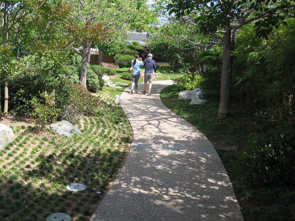 A couple moves forward down a winding path through the Japanese Friendship Garden.