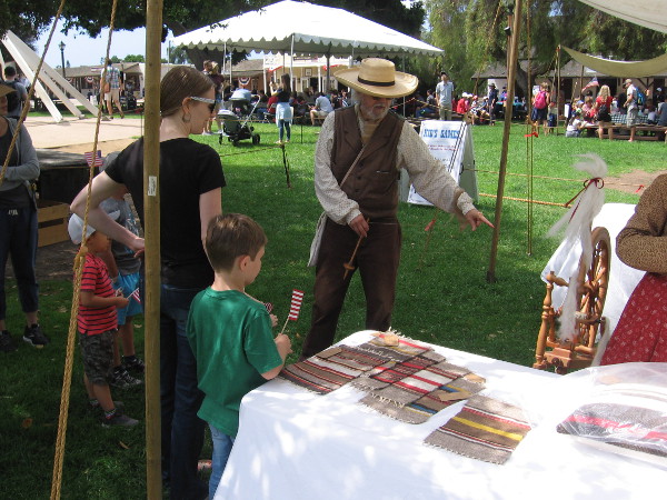 A family at Old Town's Fourth of July event learns all about spinning yarn.