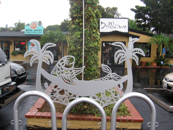 A fish in a hammock stretched between metal trees by a parking lot.