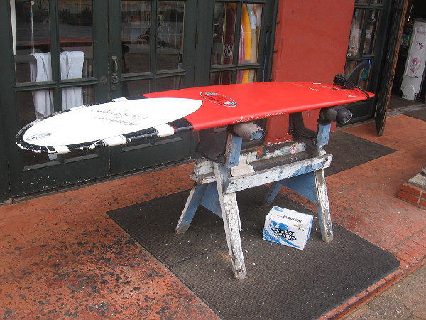 A surfboard in front of Progression Surf.